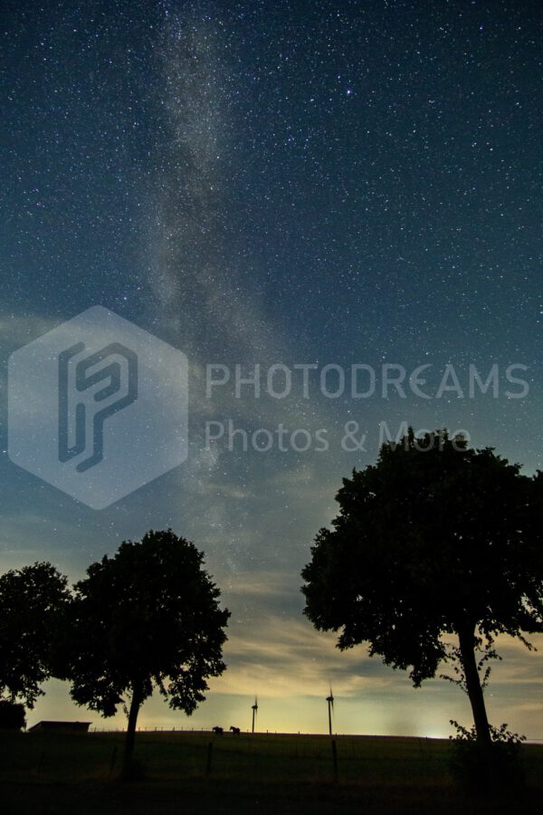 Milky Way with trees and wind wheels in Germany